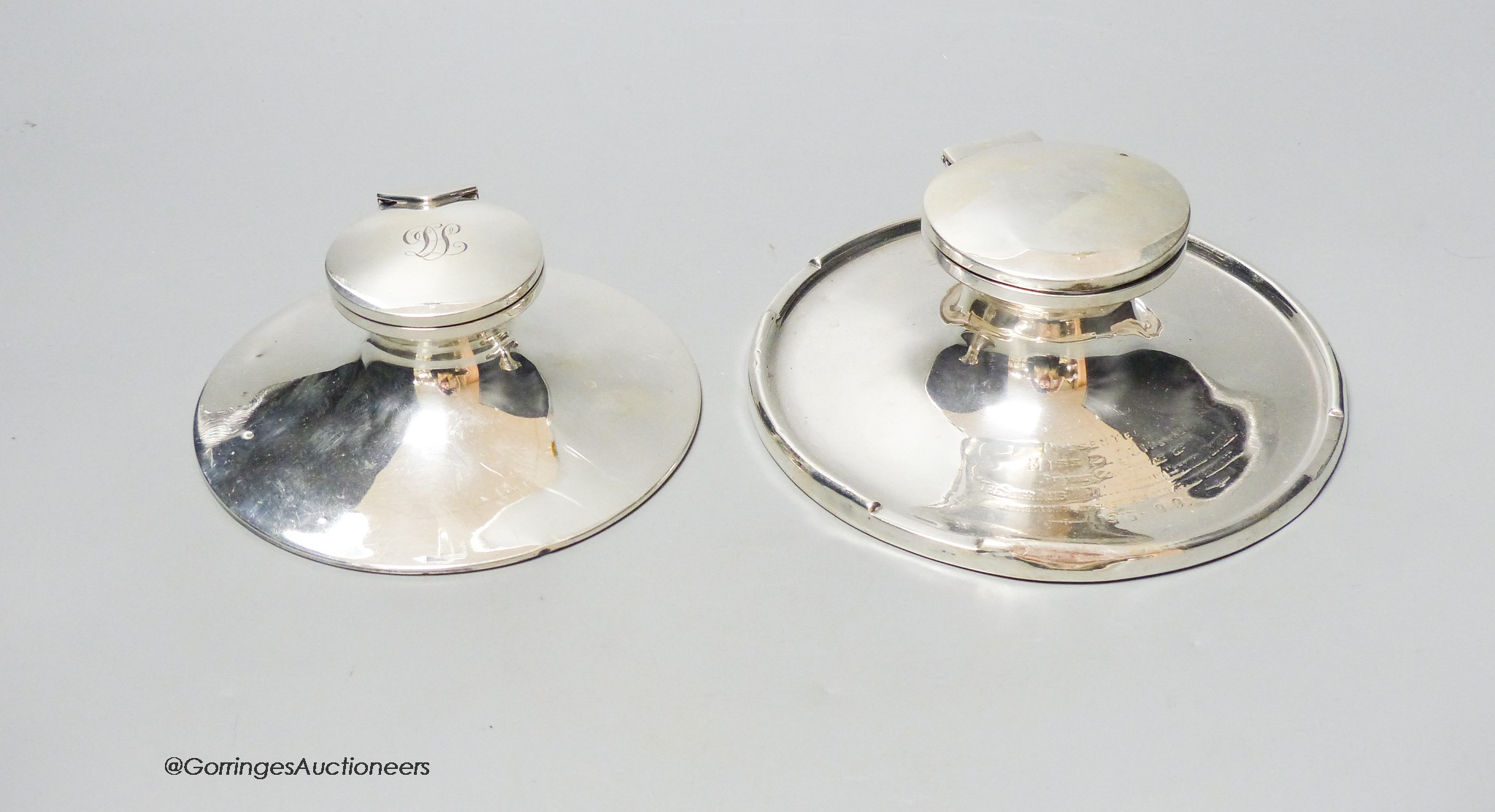 Two George V silver mounted capstan inkwells, marks rubbed, largest diameter 15.3cm.